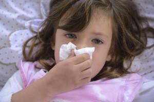 Sick little girl sneezing in bed