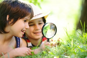 Happy kid exploring nature with magnifying glass